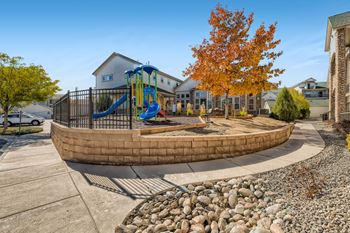 A playground with a slide and a treeat Fox Run Lofts Apartments, Englewood CO
